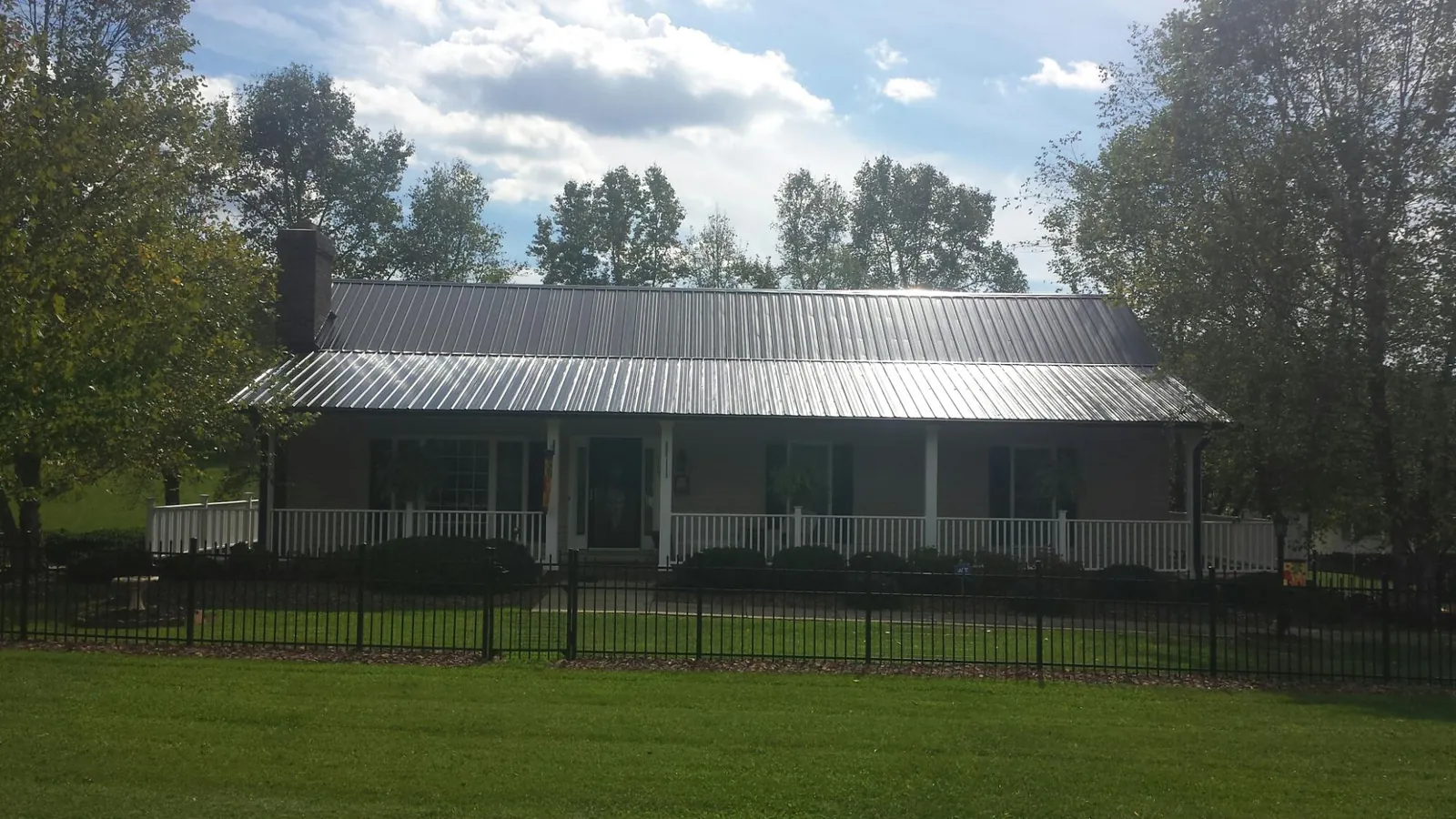 Gray metal roof on a brick ranch with a full width front porch — Gutter Guard Installation work by our crew in Ferdinand
