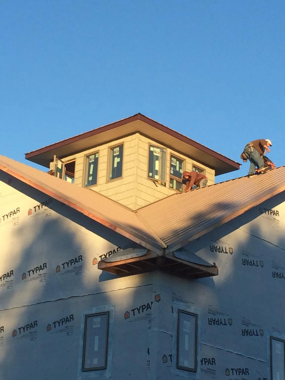 Roofers working around a rooftop cupola on a new metal roof at sunset — Roof Waterproofing in Ferdinand by Roofing Brothers